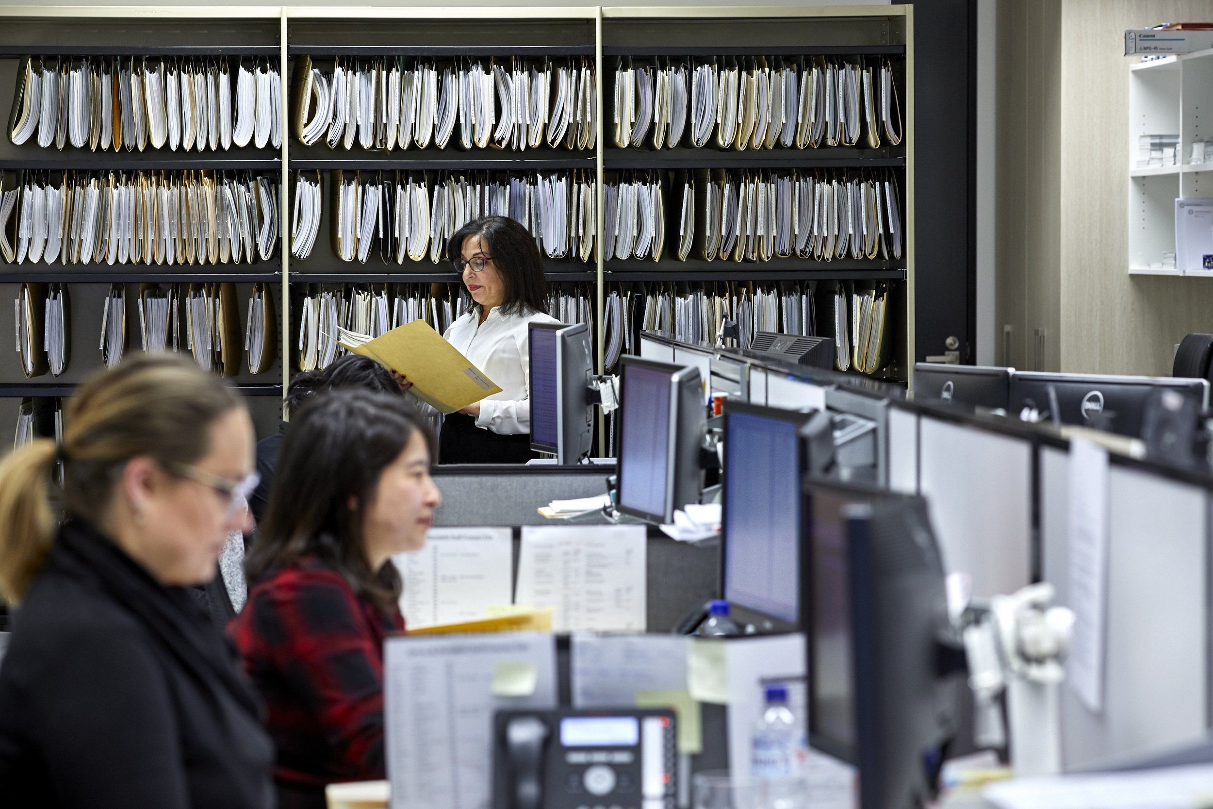 Staff at work among the filing shelves in the Green & Sternfeld office