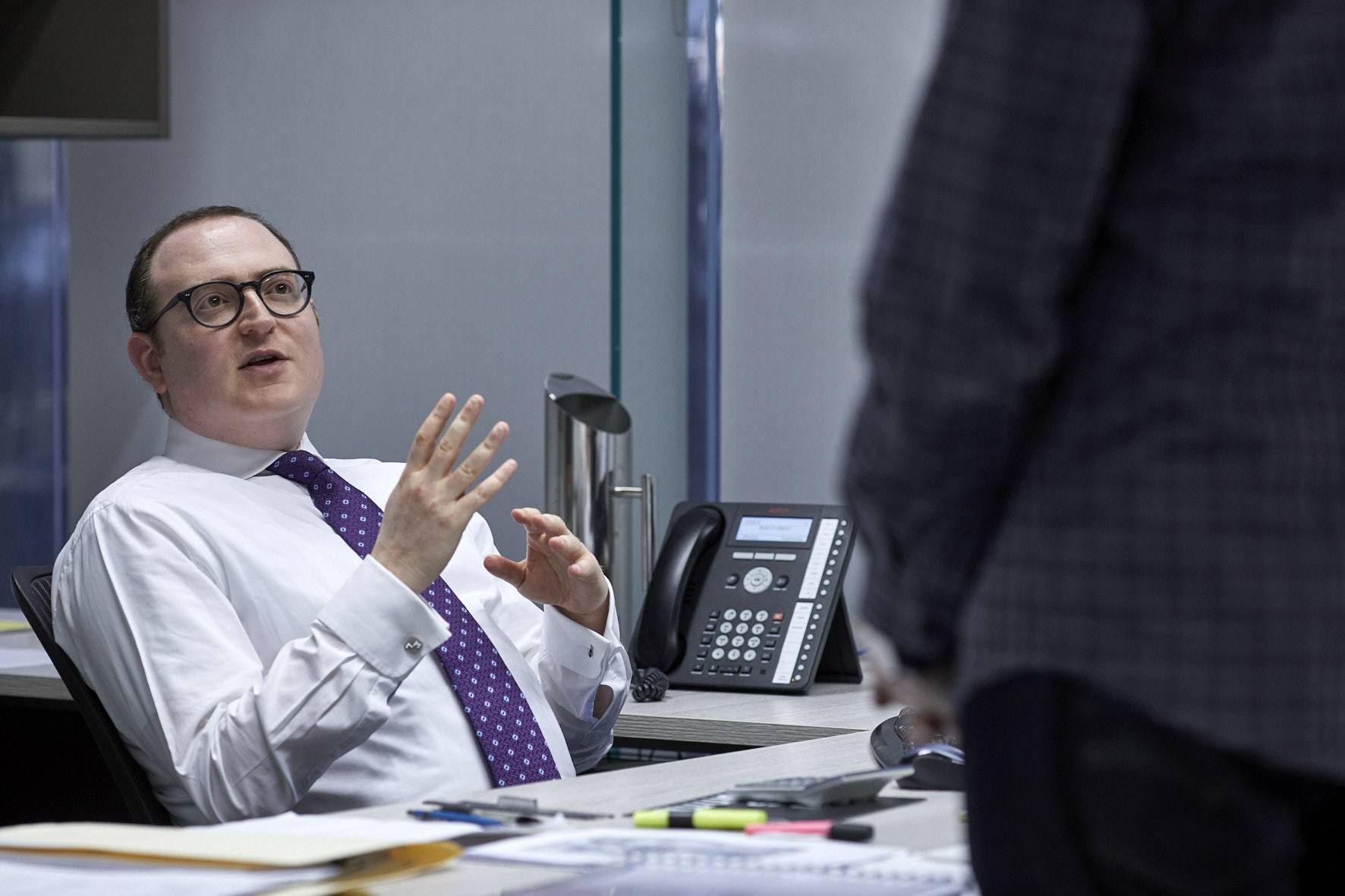 Eli Lebovits, director of Green & Sternfeld, talking with a colleague at his desk